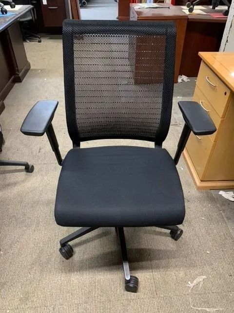Black office chair with mesh back and adjustable armrests.