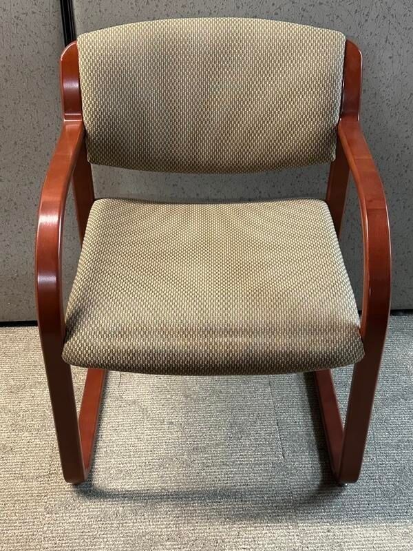 Wooden office chair with tan fabric seat and back, on a neutral-colored floor.