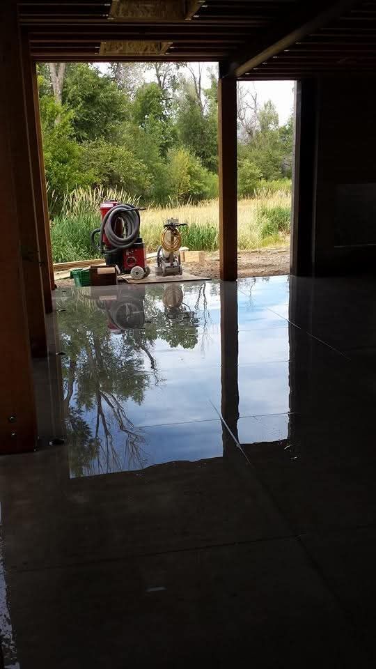 There is a reflection of trees in the floor of the garage.