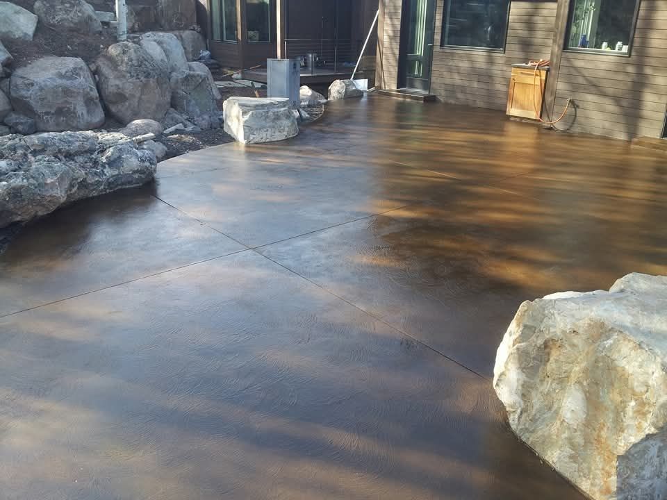 A concrete patio with rocks and a house in the background