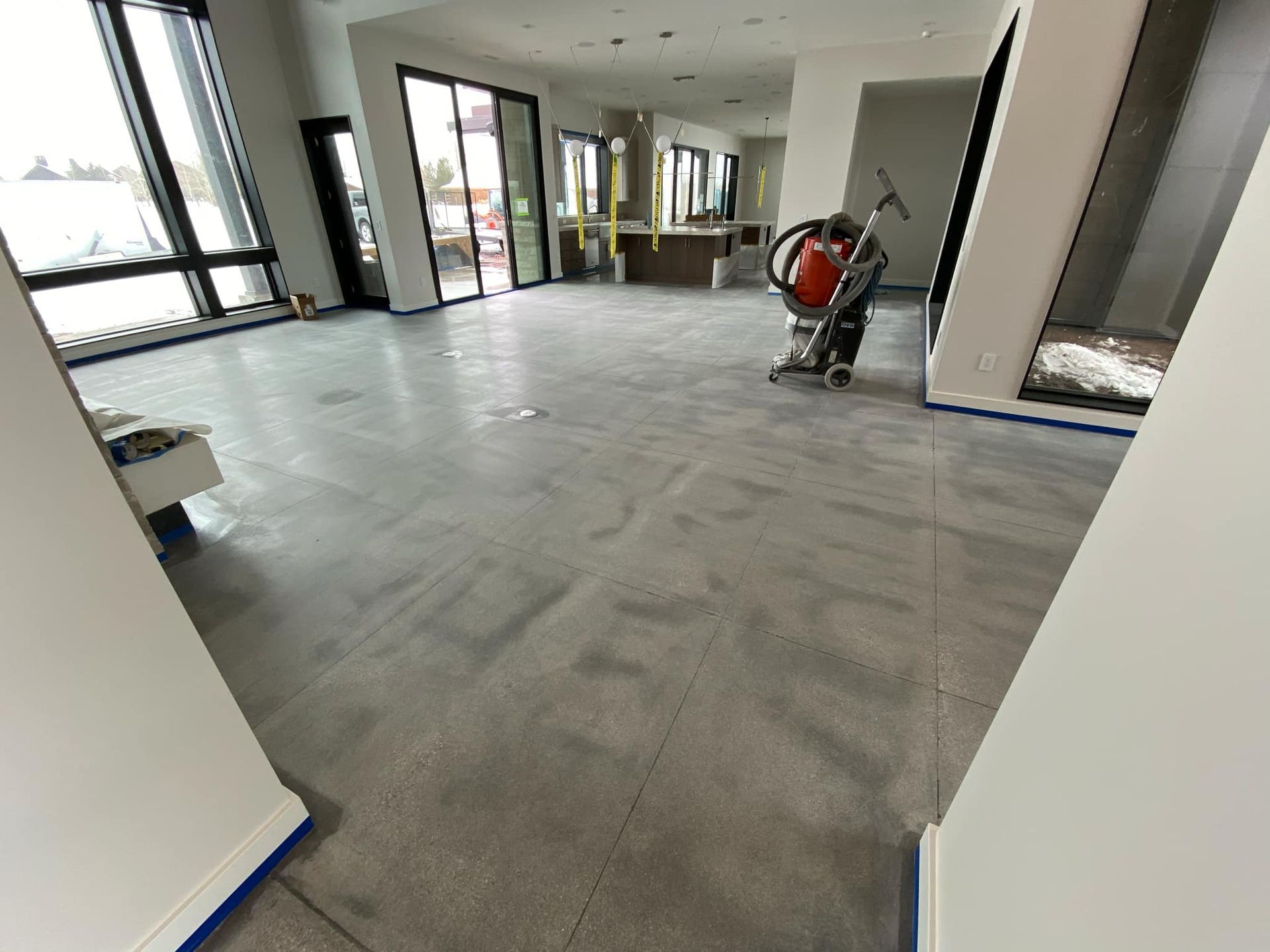 A man is using a vacuum cleaner to clean a concrete floor.