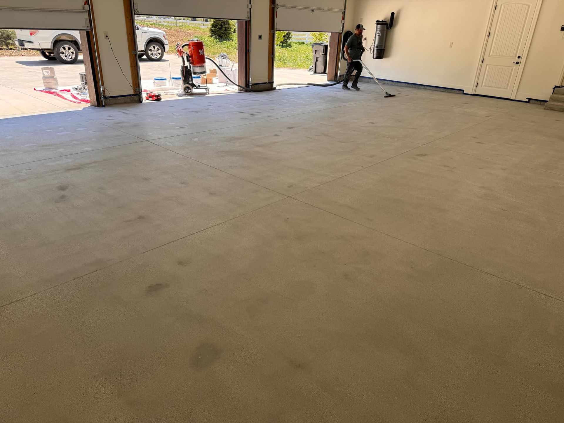 A man is cleaning the floor of a garage with a vacuum cleaner.