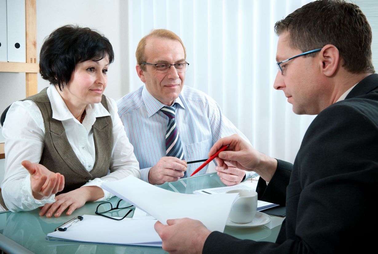 A financial advisor reviewing documents with a couple at a desk.