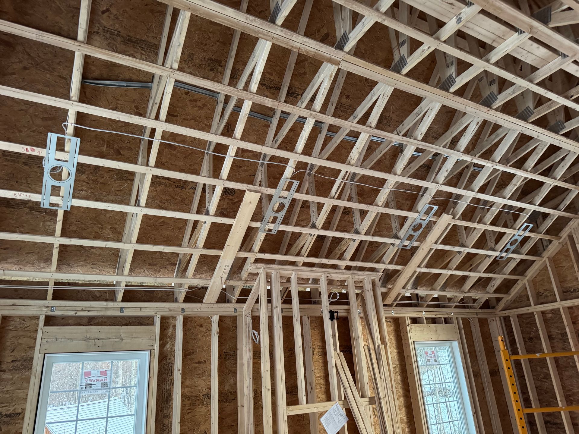 Wooden framework of a building's ceiling and walls under construction; electrical boxes and wiring are visible.