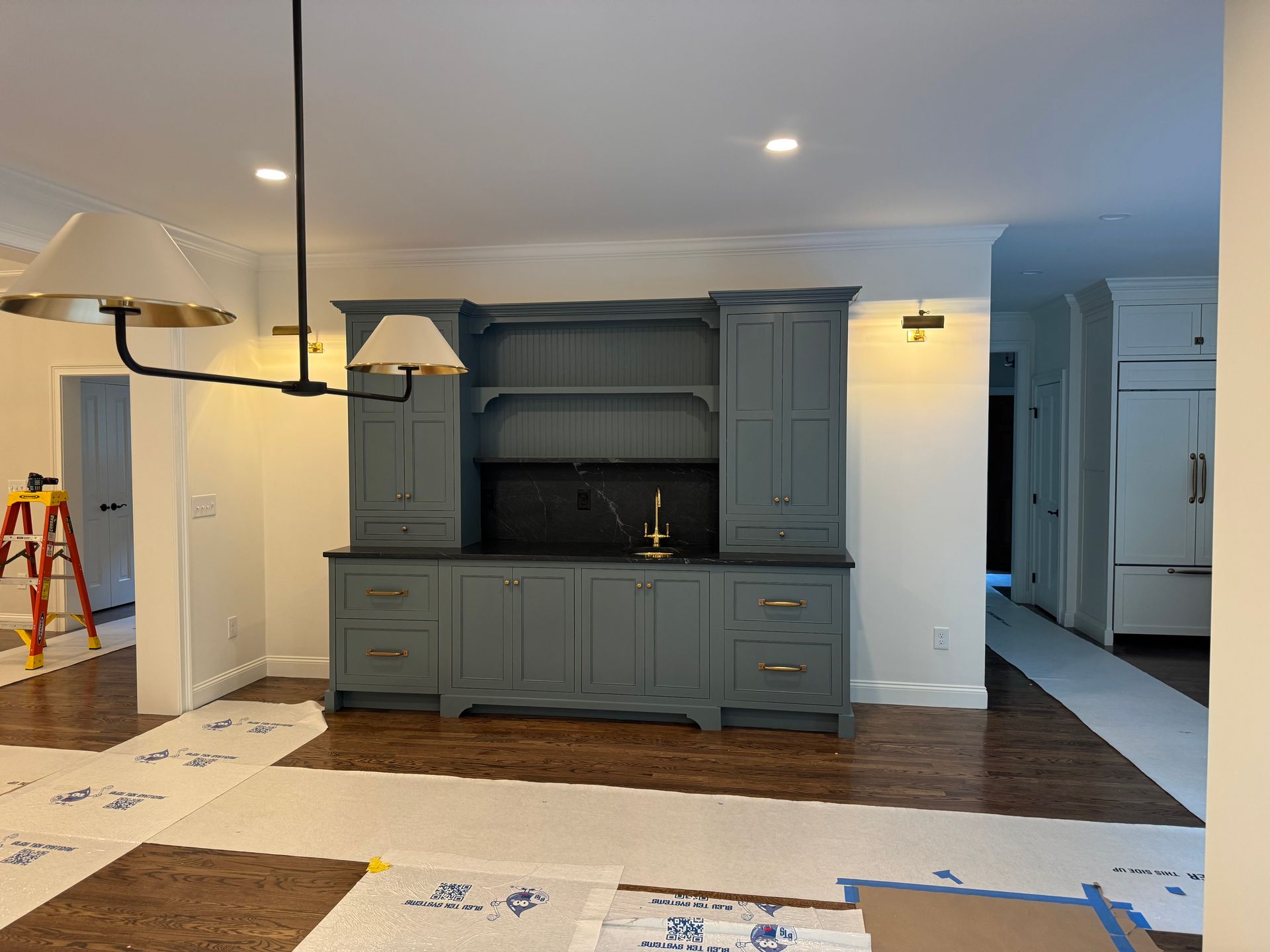 Blue cabinet built-in with a dark countertop and open shelving in a room with hardwood floors and a chandelier.