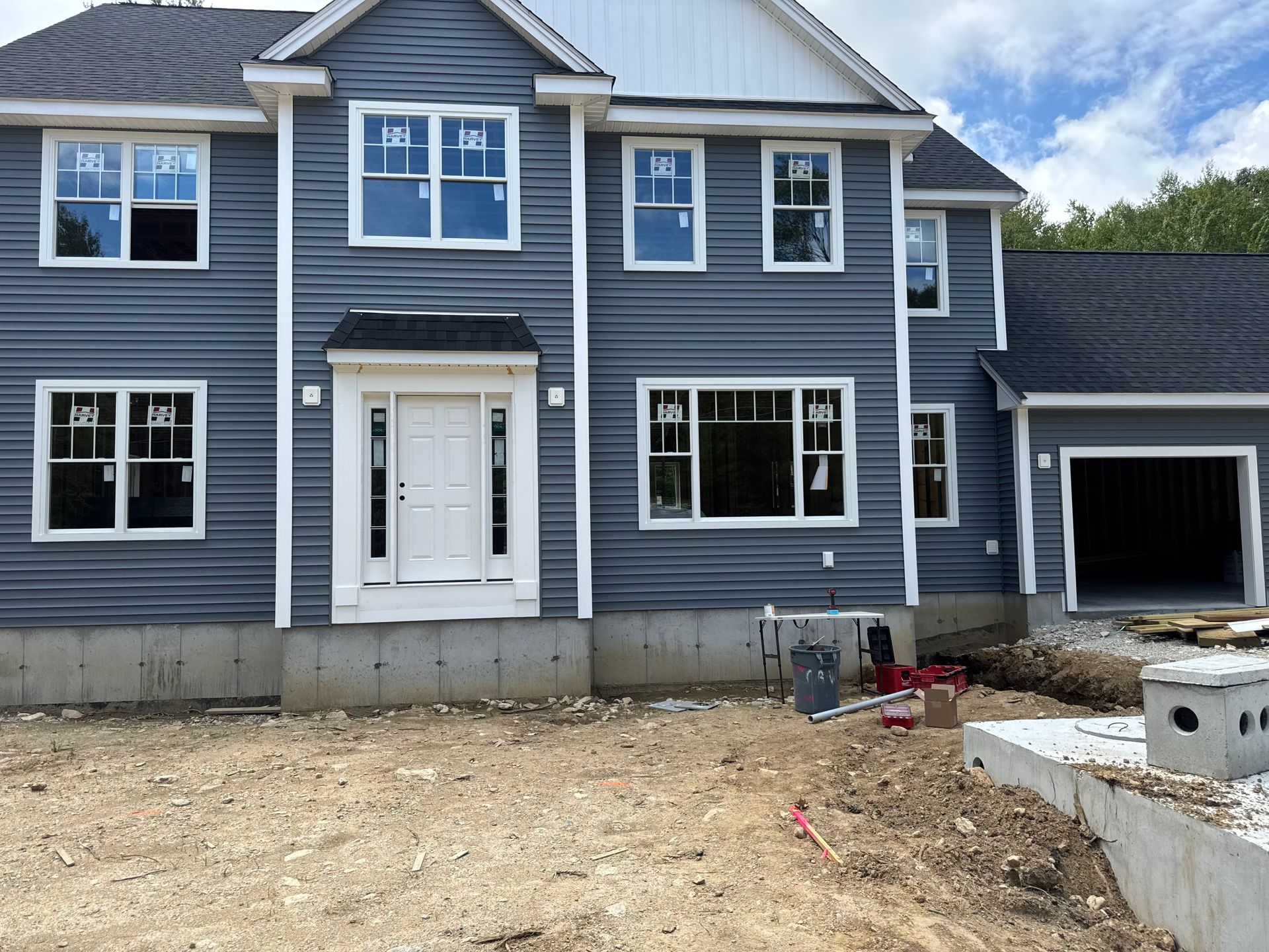 New construction home with blue siding, white trim, and a partially open garage.
