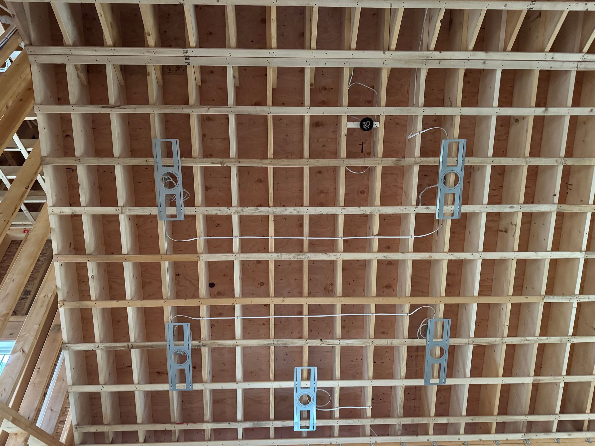 Wooden ceiling framing with metal brackets and electrical wiring.