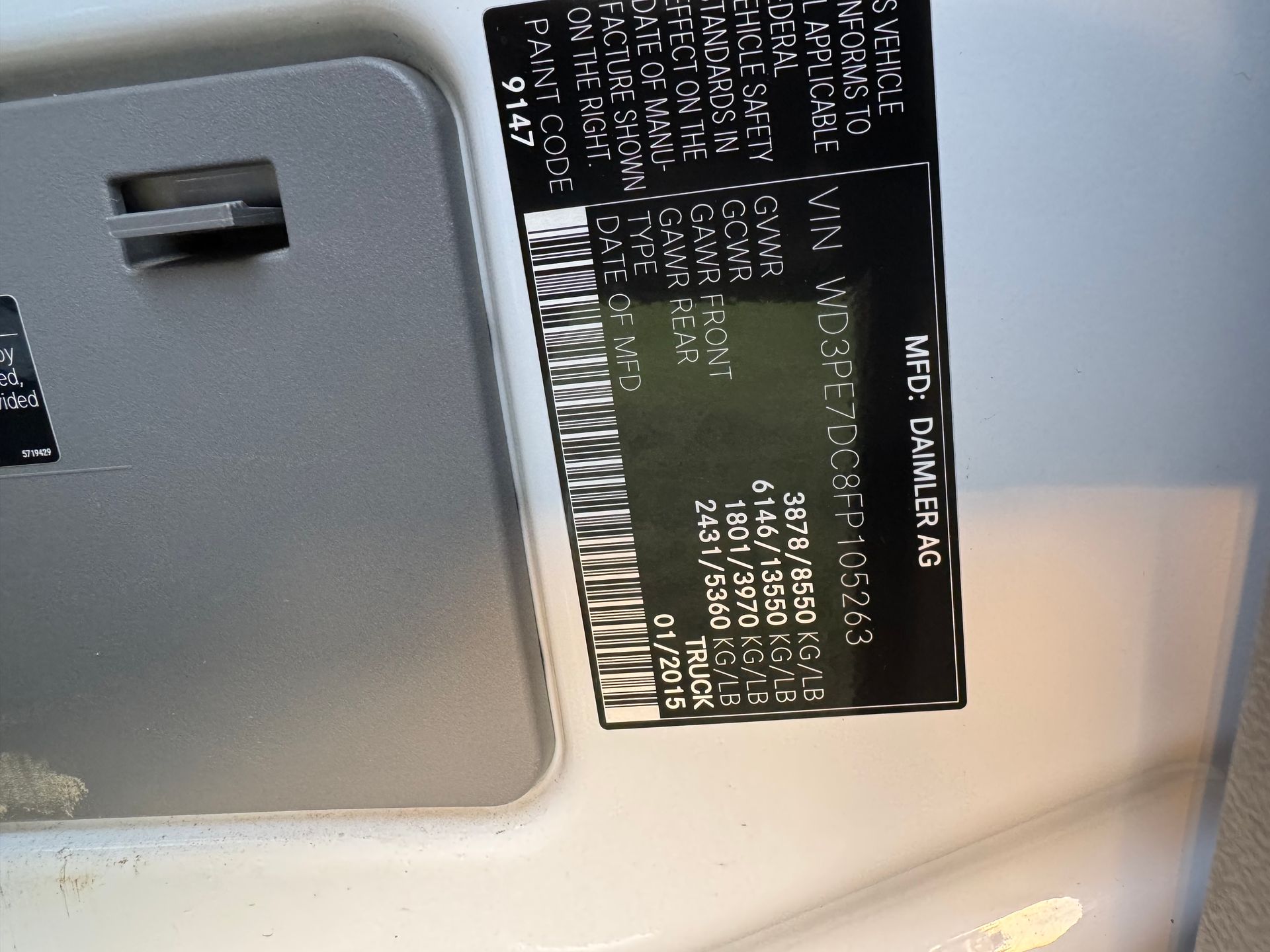 Vehicle identification sticker on a light-colored surface with black text and barcodes.