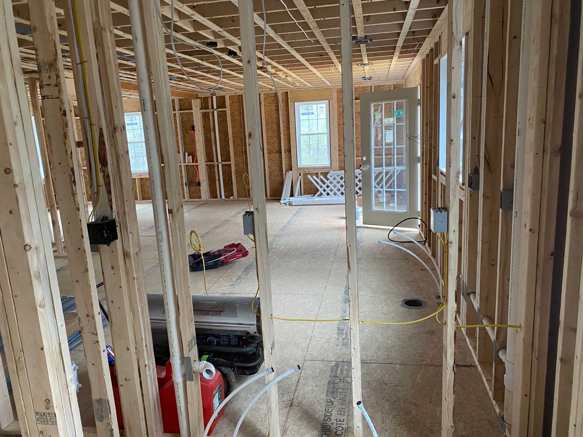 Interior framing of a house under construction. Wooden studs, electrical wiring, and open doorways.