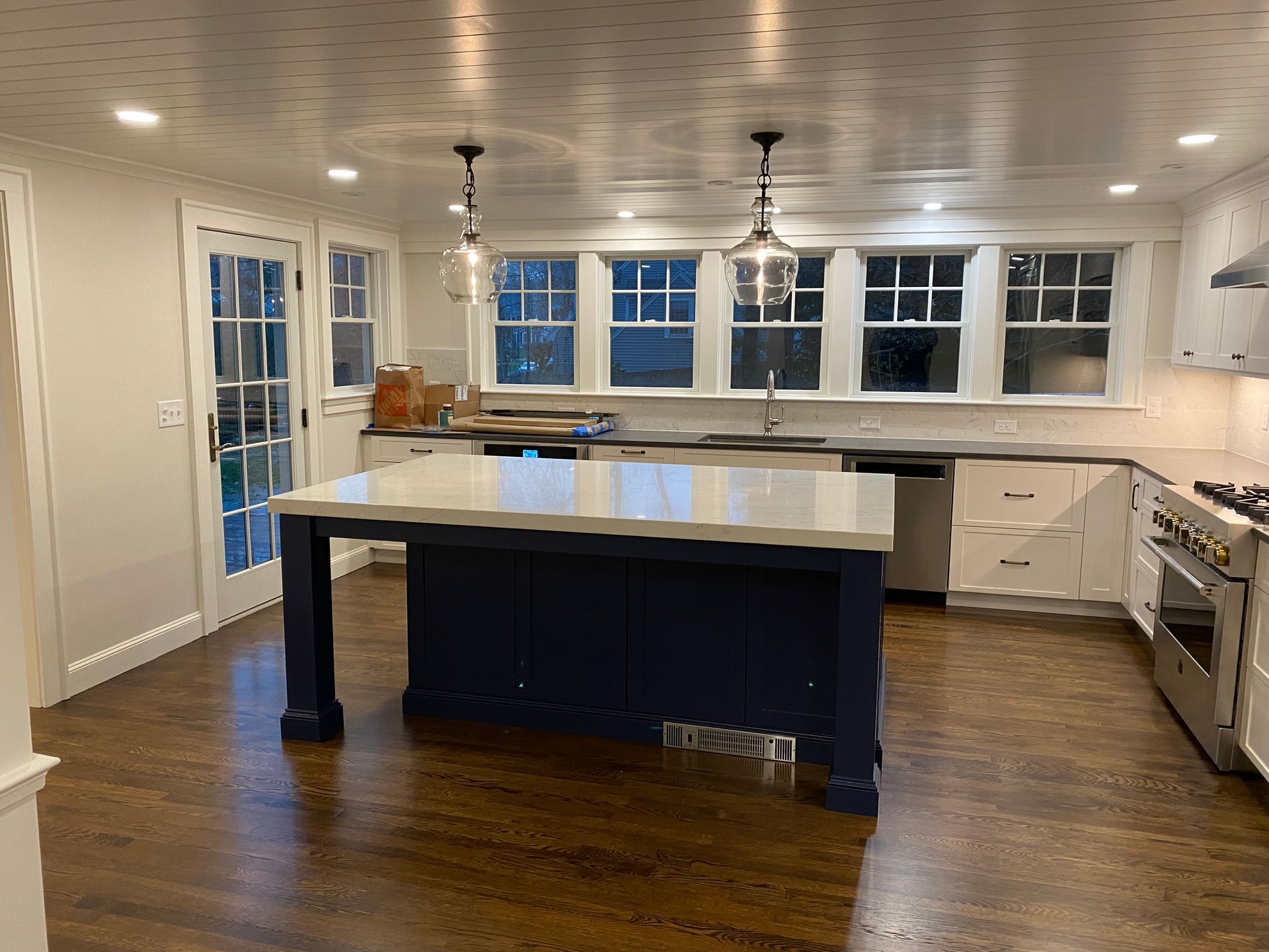 Kitchen with blue island, white cabinets, and wood floors.
