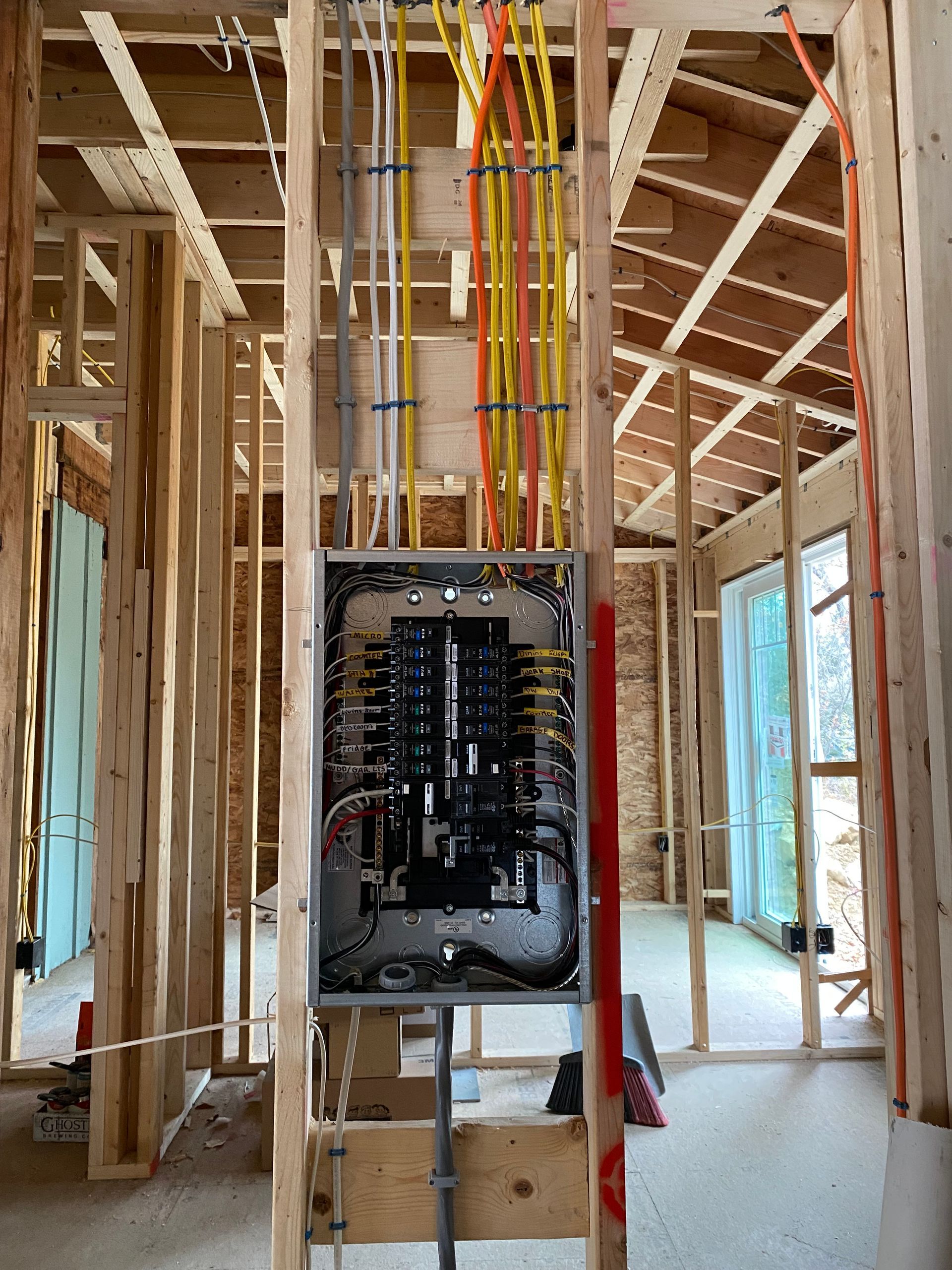 Electrical panel installed in a house under construction; wires run vertically.