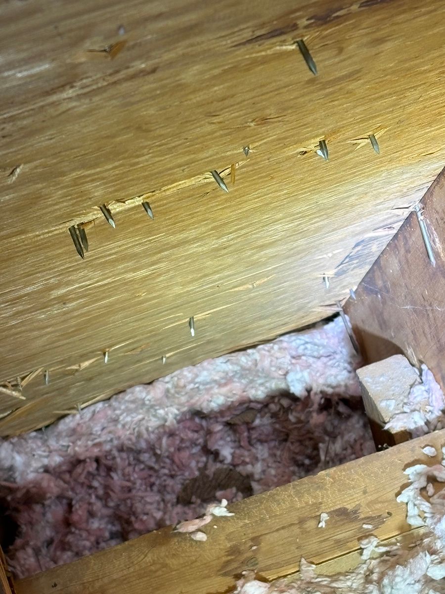 Close-up of damaged wooden beam with a narrow crack and exposed insulation underneath
