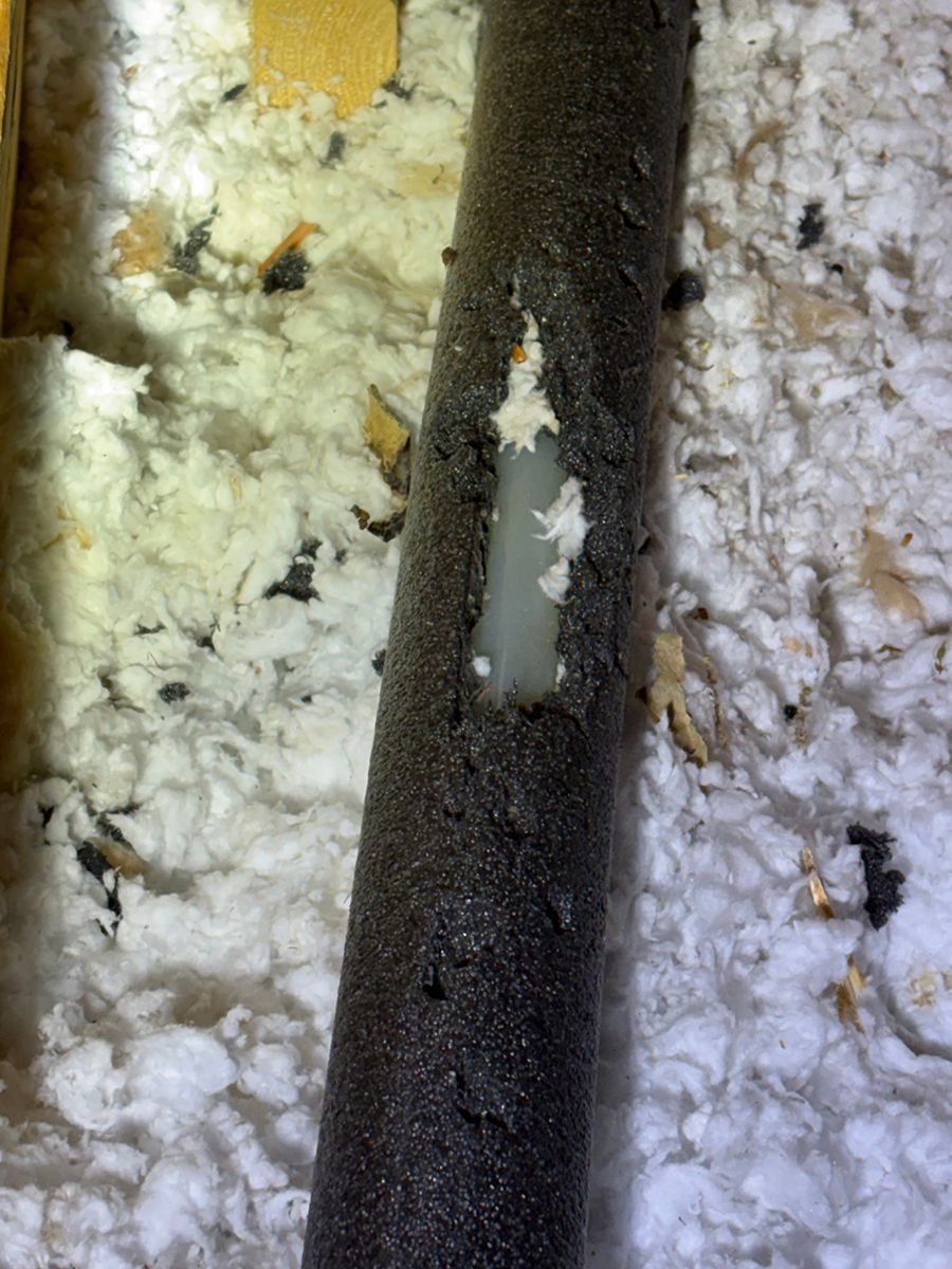 Close-up of a black metal pole with a chipped white patch, surrounded by snow and a yellow object.