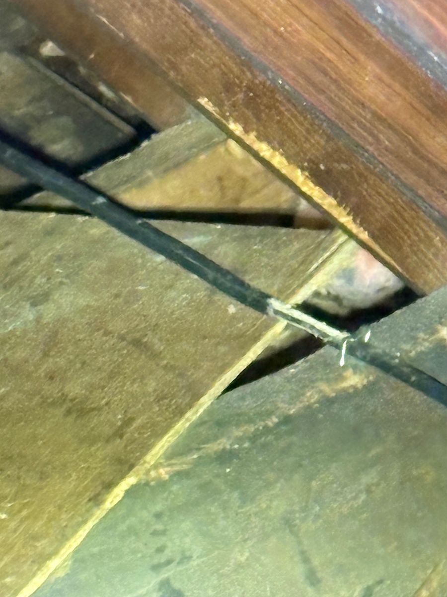 Close-up of dusty wooden floorboards with a black cable crossing between them