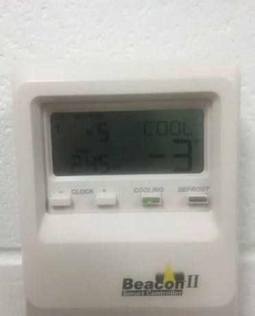 A white Beacon II smart controller on a wall showing a -3 temperature setting with a 