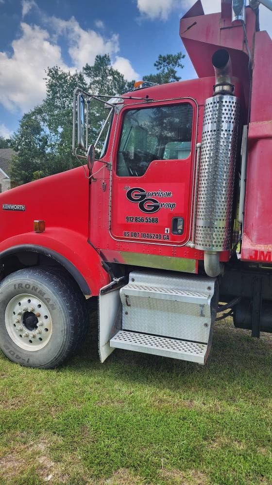 Red dump truck on grass, with company logo on the door and a large exhaust pipe.