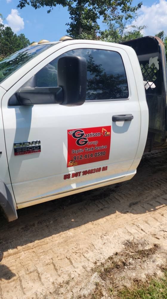 White work truck with red company logo on the door parked on dirt.