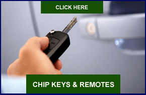 A person is holding a car key in front of a car.