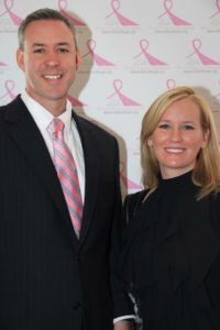 A man in a suit and tie stands next to a woman in a black dress