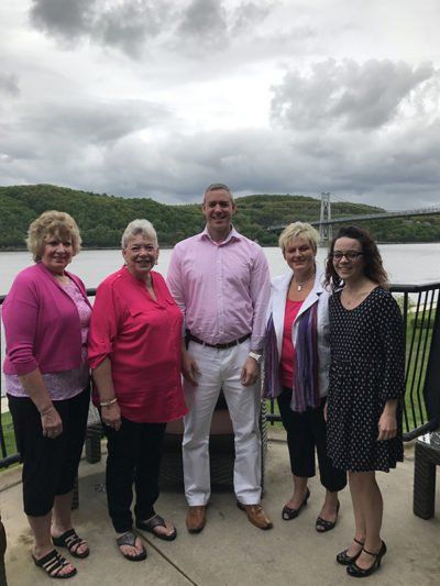 A group of people are posing for a picture in front of a lake.
