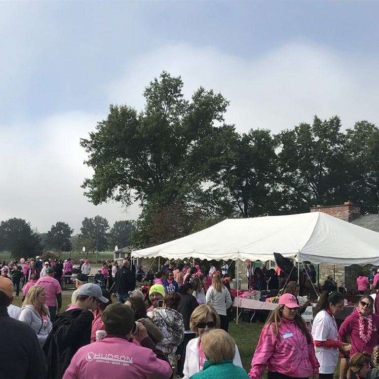 A large group of people are gathered under a white tent