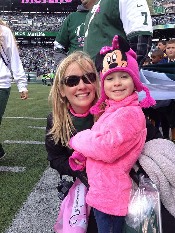 A woman is holding a little girl wearing a mickey mouse hat
