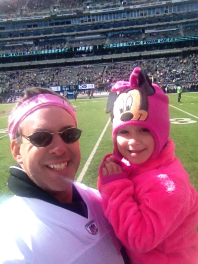A man holding a little girl wearing a pink mickey mouse hat
