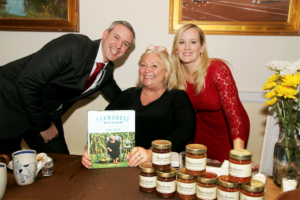 A man and two women are standing around a table holding a book