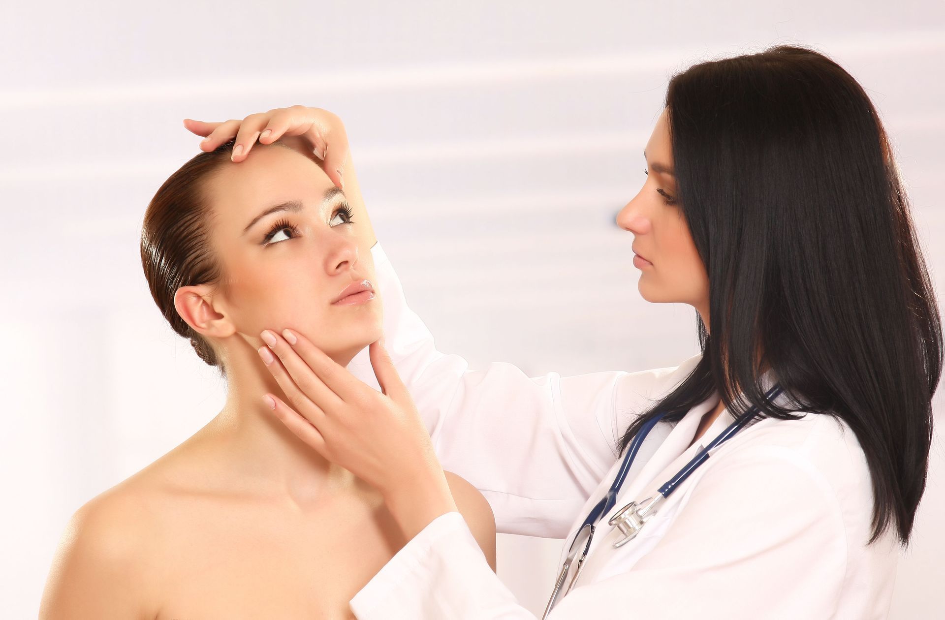 A female doctor is examining a woman 's face.