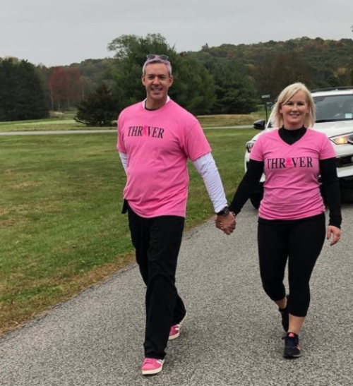 A man and a woman are holding hands while wearing pink shirts that say thriver