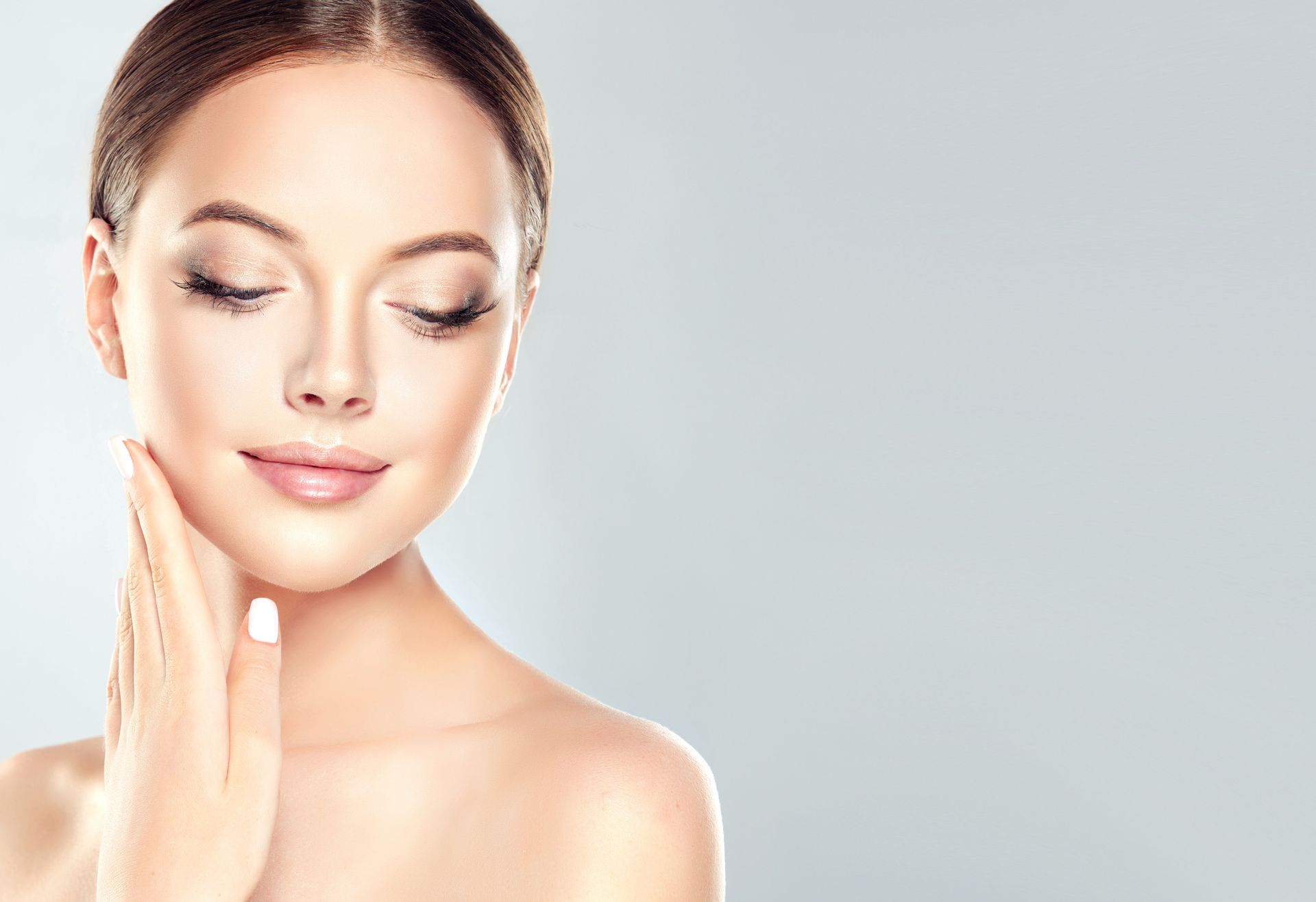 A woman is touching her face with her hands and smiling.