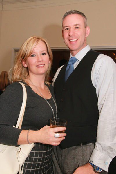 A man and a woman are posing for a picture and the woman is holding a glass