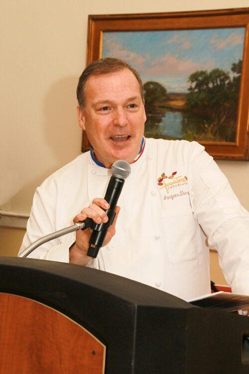 A man in a chef 's uniform is speaking into a microphone