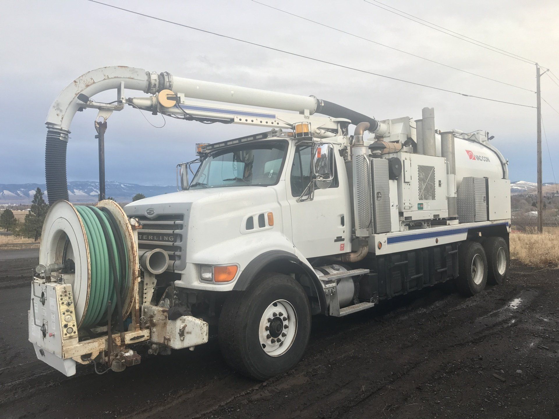 A white vacuum truck is parked on the side of the road.