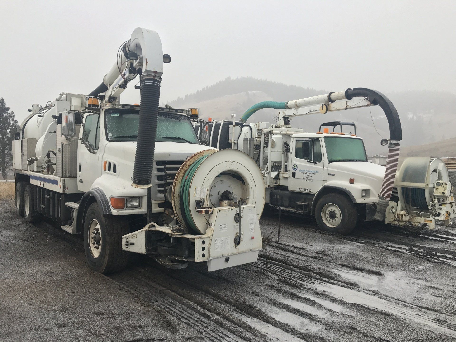 Two trucks are parked next to each other on a dirt road.