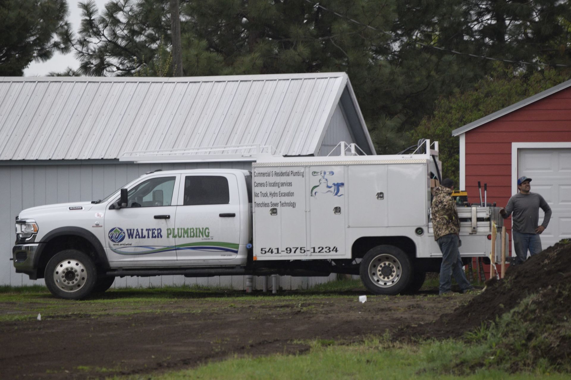 A walter plumber truck is parked in front of a red barn.