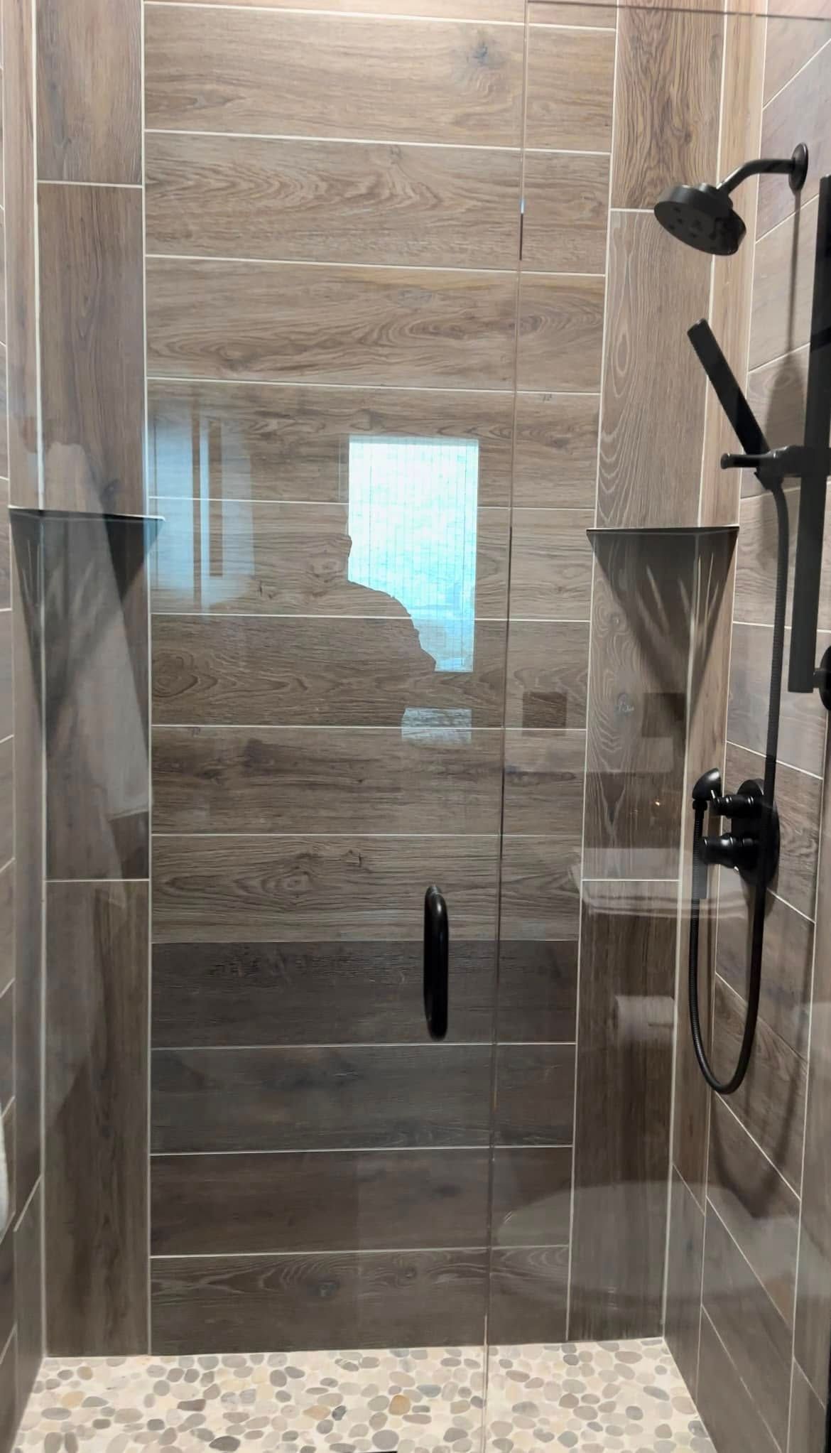 A bathroom with a glass shower door and a shower head