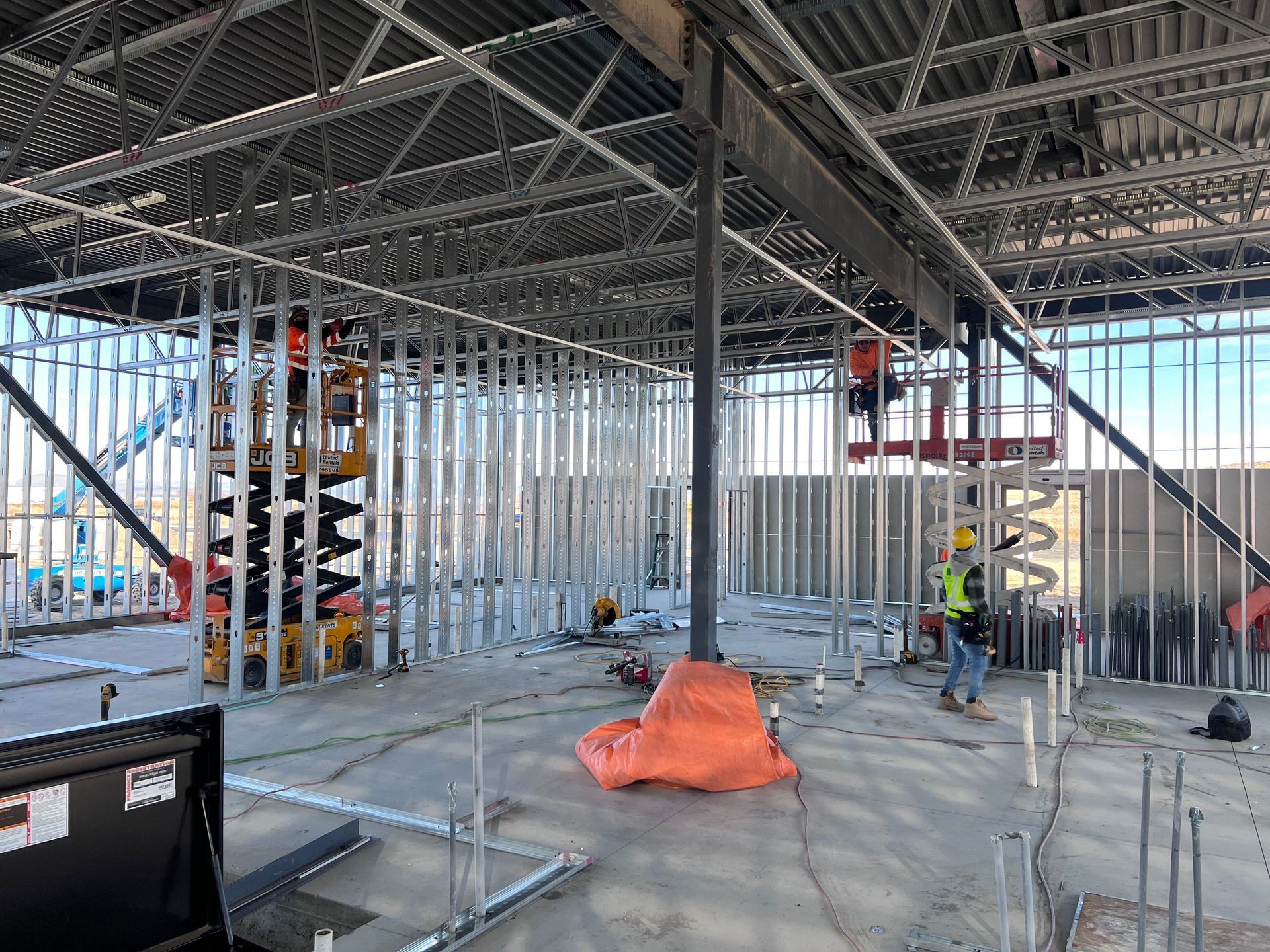 A construction site with a lot of steel frames and workers.
