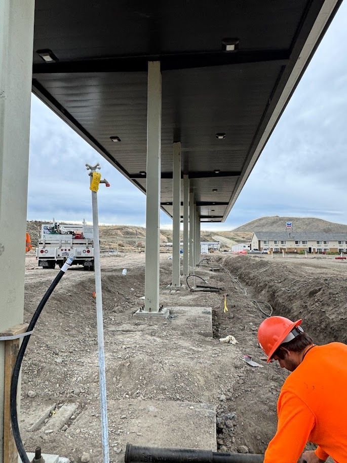 A man wearing an orange shirt and hard hat is working on a construction site.