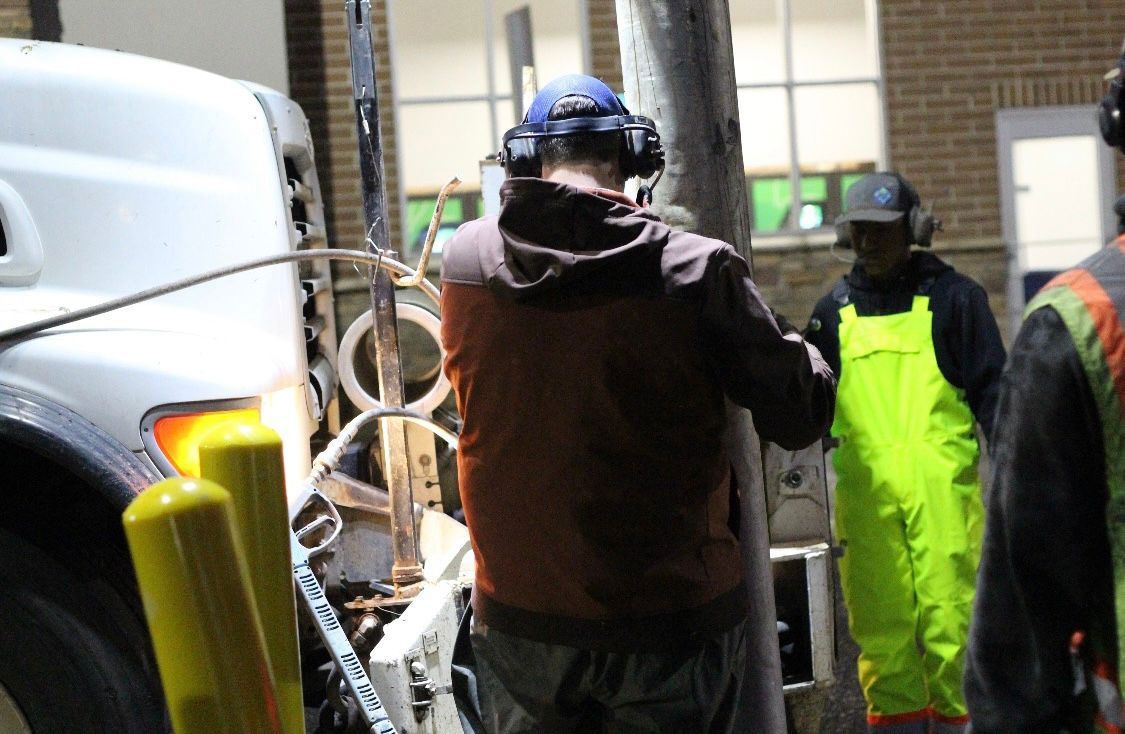 A group of construction workers are standing in front of a white truck.