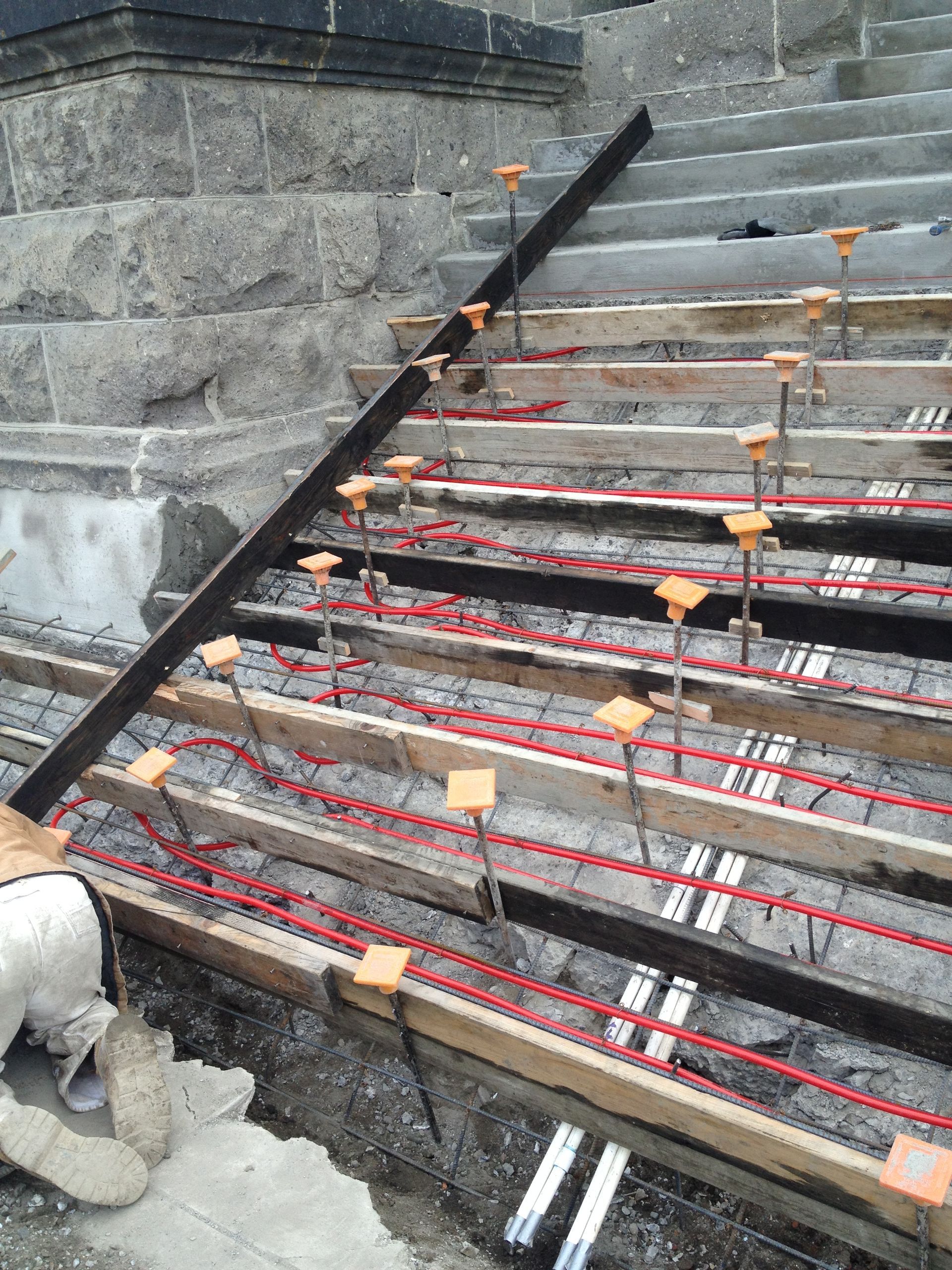A man is in the process of installing a snowmelt system on a newly constructed staircase.