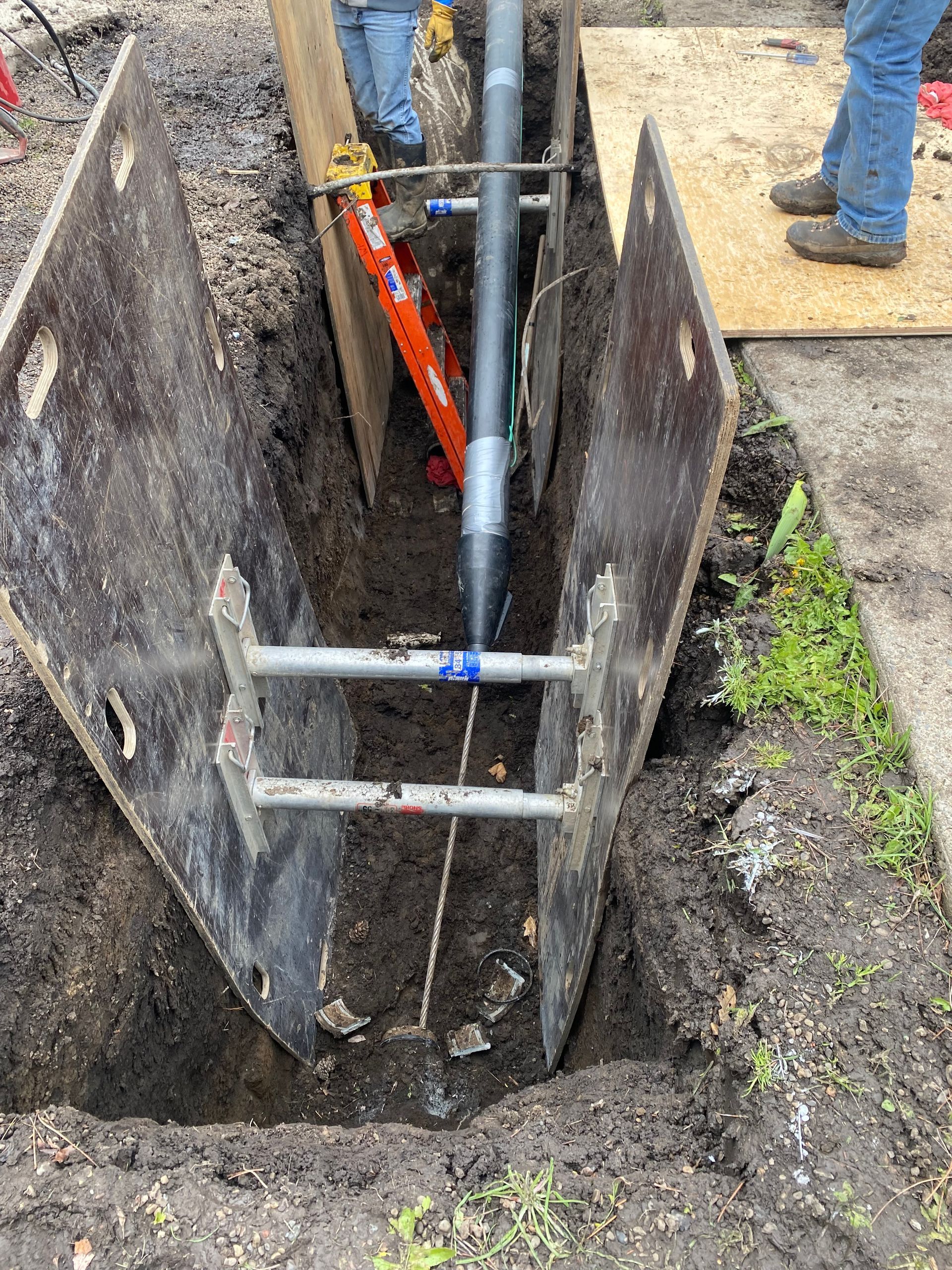 A pipe is being installed in a trench with a ladder.