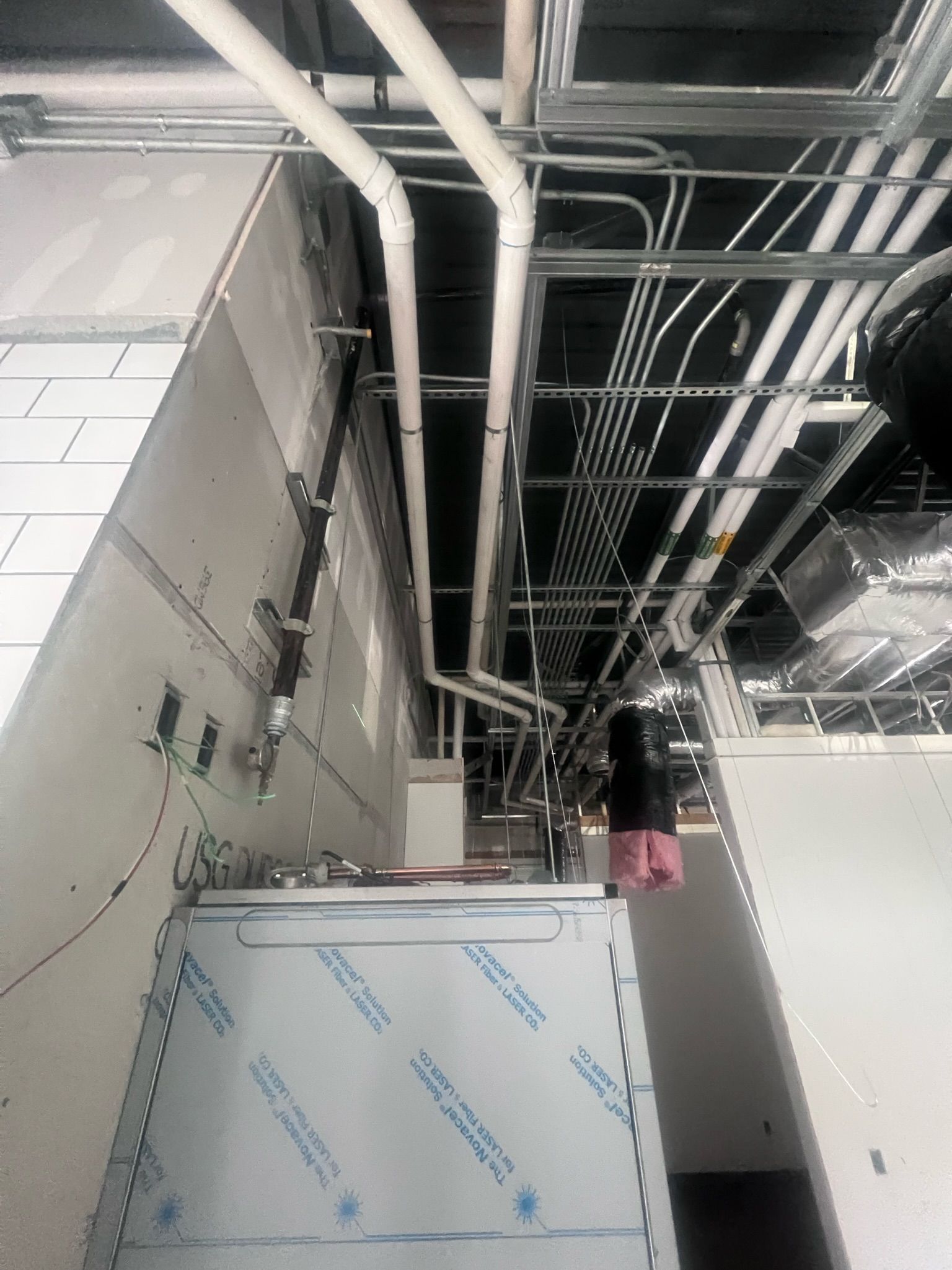 A bunch of pipes are hanging from the ceiling of a building