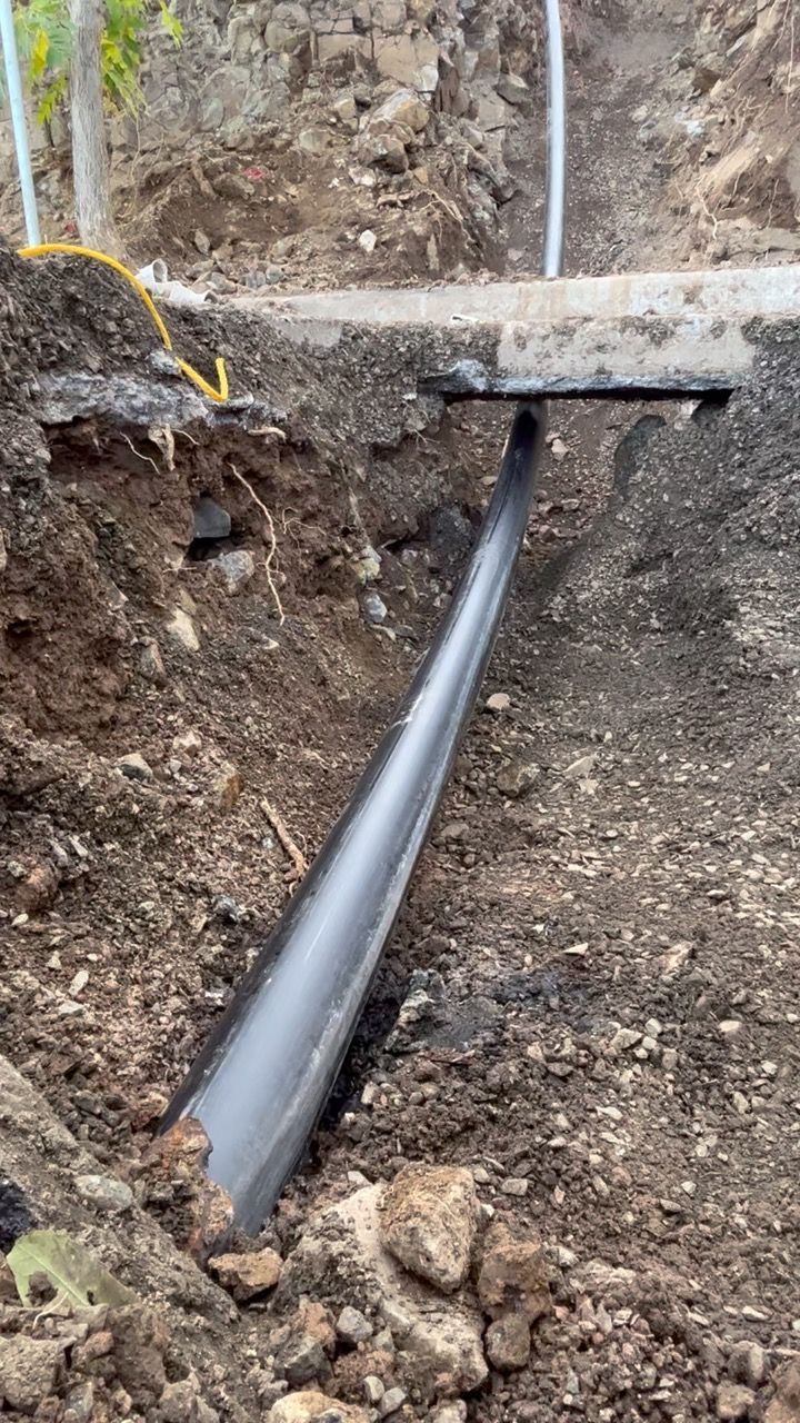 A pipe is laying in the dirt in a hole