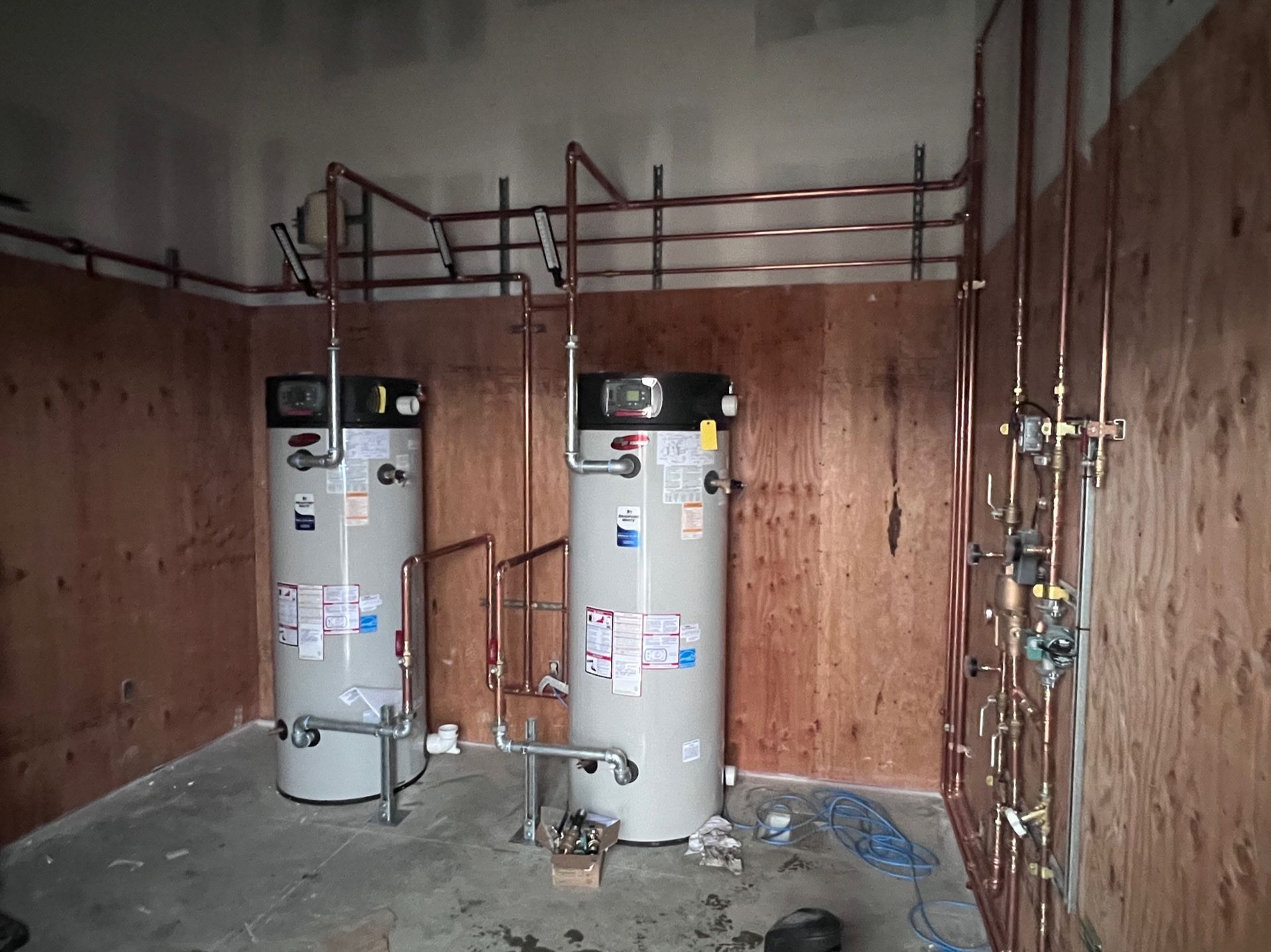 Two water heaters in a room with copper pipes