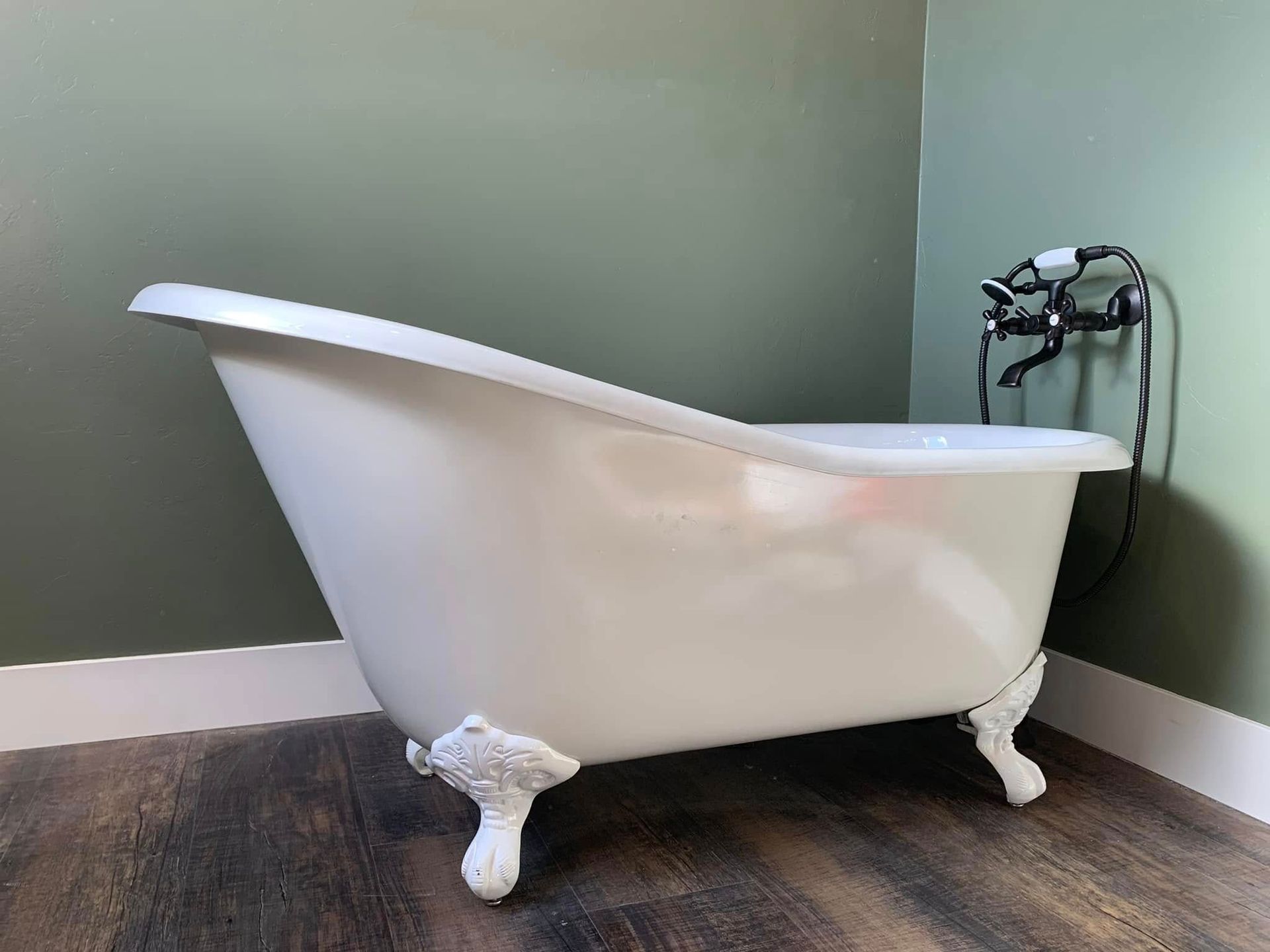 A white bathtub is sitting on a wooden floor in a bathroom