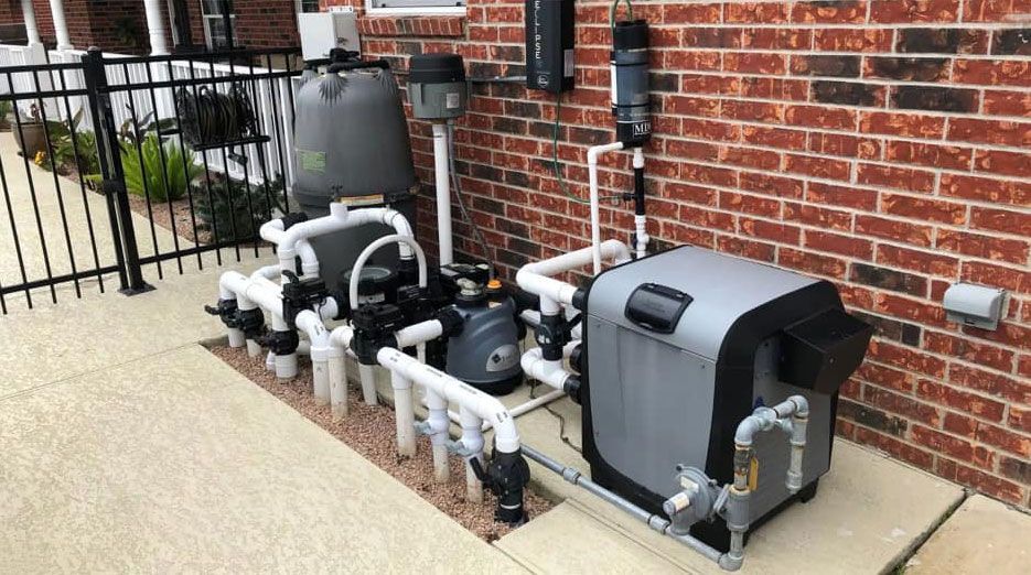 Pool equipment set against a brick wall, featuring a filter, pump, and heater with white and gray components.