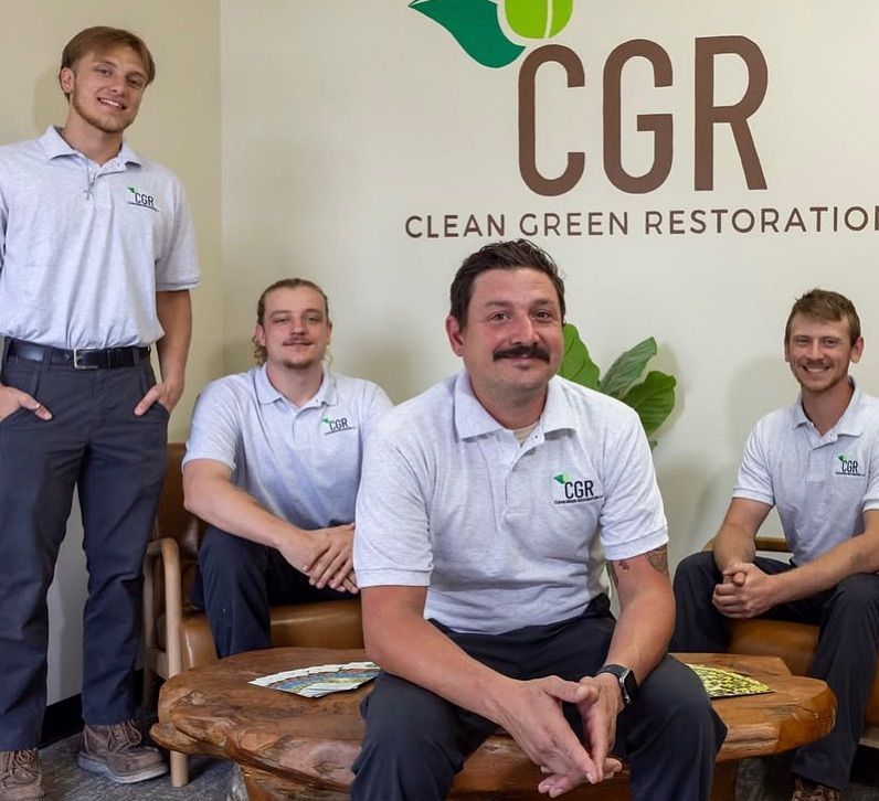 Four men in matching shirts pose in front of a logo for 