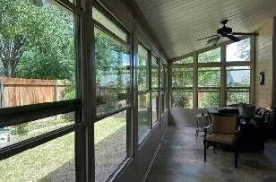 A sun room with a lot of windows and a ceiling fan.