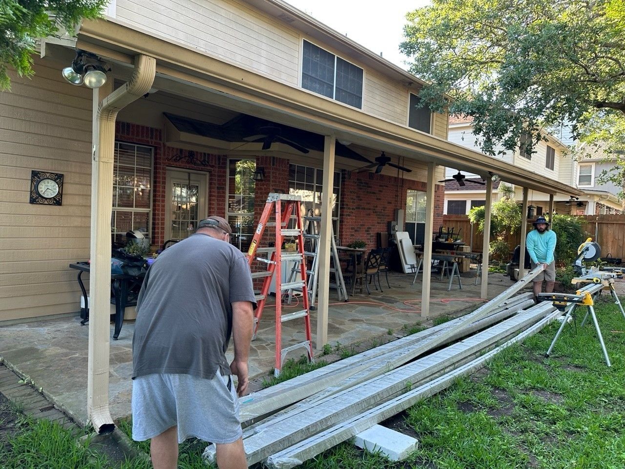 A man is standing next to a ladder in front of a house.